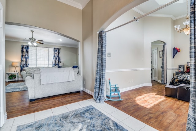 tiled living room with ornamental molding and ceiling fan with notable chandelier