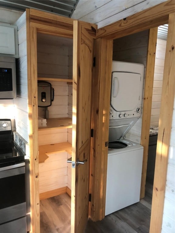 washroom with stacked washer and dryer, wood walls, and dark wood-type flooring