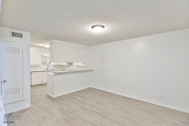 interior space featuring a textured ceiling, light wood-type flooring, white cabinets, and dishwasher