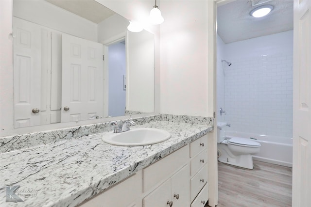 full bathroom with tiled shower / bath, toilet, vanity, and hardwood / wood-style flooring