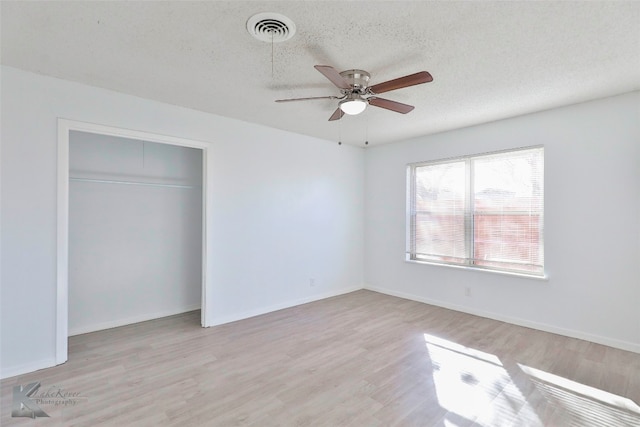 unfurnished bedroom with a closet, a textured ceiling, ceiling fan, and light hardwood / wood-style flooring