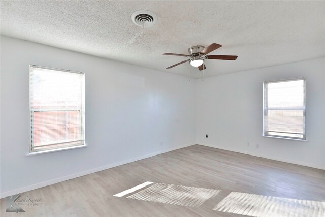 unfurnished room featuring ceiling fan, a textured ceiling, light hardwood / wood-style flooring, and a healthy amount of sunlight