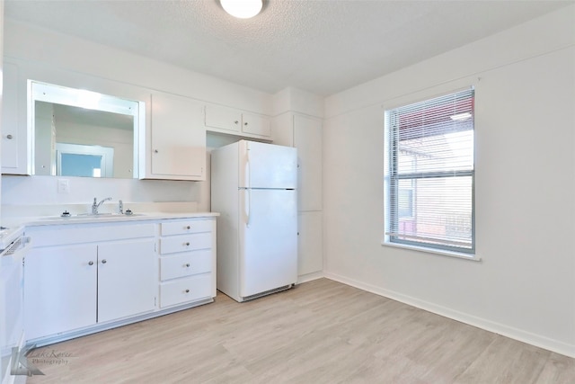 kitchen featuring white cabinets, a textured ceiling, light wood-type flooring, white appliances, and sink