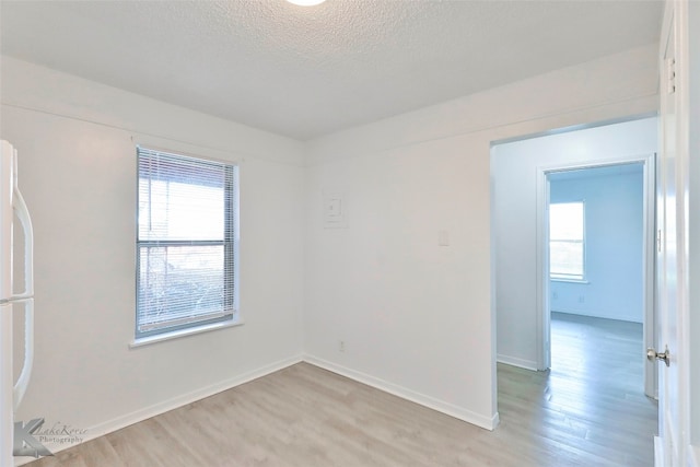 spare room featuring light hardwood / wood-style flooring, plenty of natural light, and a textured ceiling