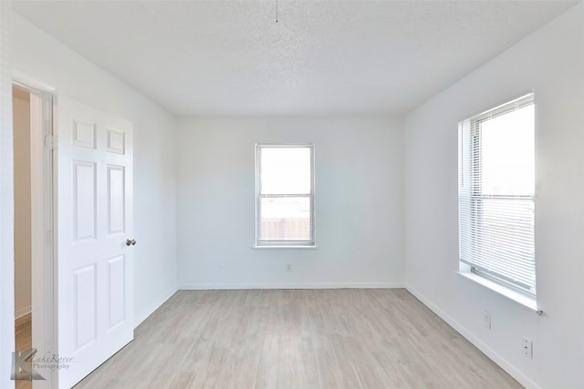 spare room with a textured ceiling and light hardwood / wood-style flooring