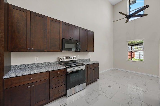 kitchen featuring ceiling fan, electric stove, light tile floors, light stone counters, and a towering ceiling