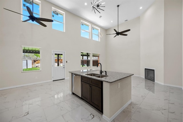 kitchen featuring a center island with sink, light tile flooring, ceiling fan with notable chandelier, and a high ceiling