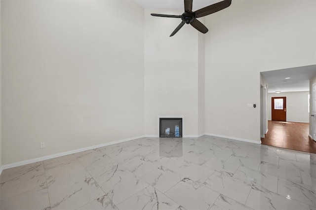 empty room with a high ceiling, ceiling fan, and light wood-type flooring