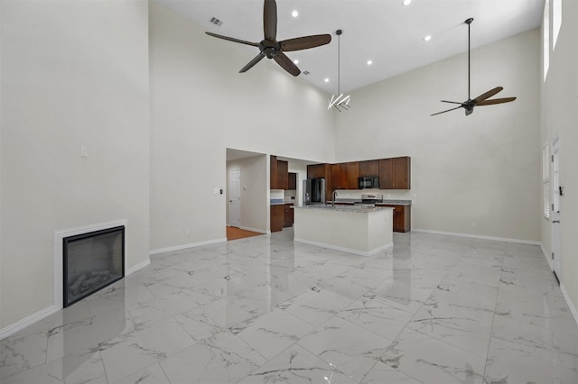 unfurnished living room with sink, high vaulted ceiling, ceiling fan, and light tile flooring