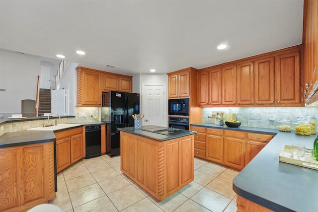 kitchen with light tile patterned flooring, black appliances, decorative backsplash, sink, and a kitchen island