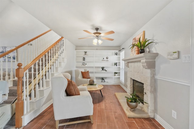 living room featuring a stone fireplace, hardwood / wood-style floors, and ceiling fan