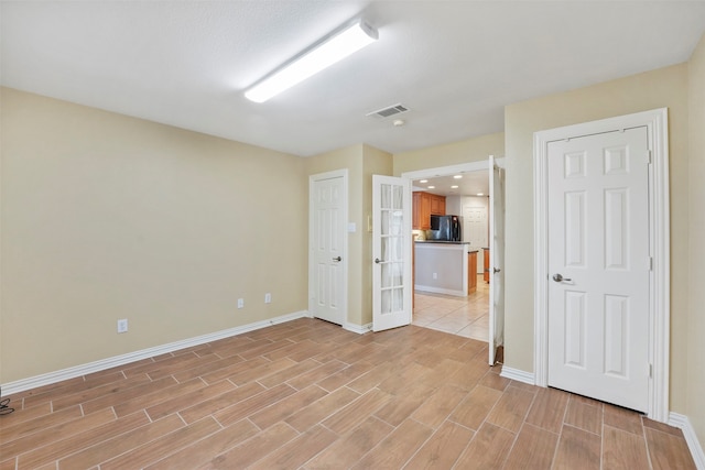 unfurnished bedroom featuring black refrigerator and light tile patterned floors