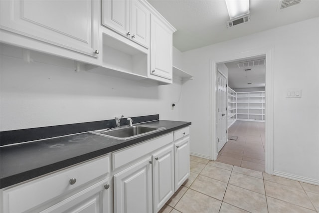 kitchen with white cabinets, light tile patterned floors, and sink