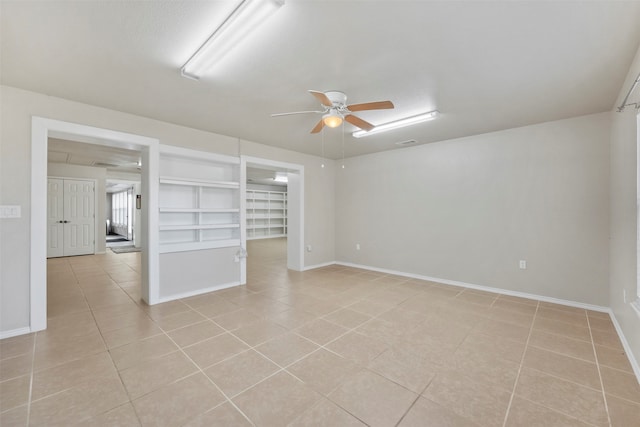 tiled spare room featuring built in features and ceiling fan