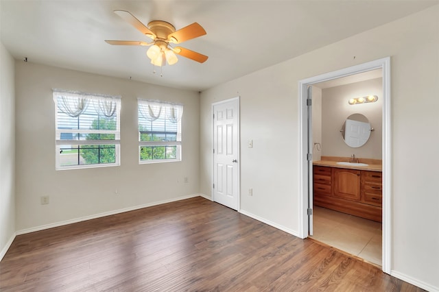 unfurnished bedroom featuring sink, ensuite bathroom, ceiling fan, and hardwood / wood-style floors