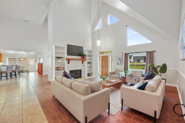 living room with built in shelves, a fireplace, and a high ceiling