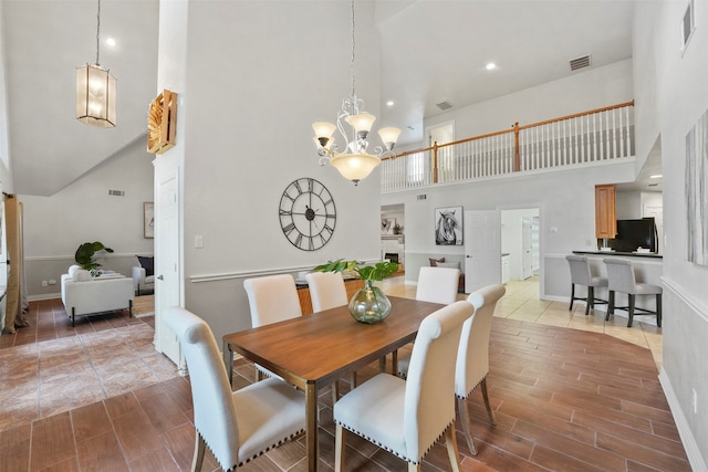 dining area with an inviting chandelier, tile patterned floors, and a towering ceiling