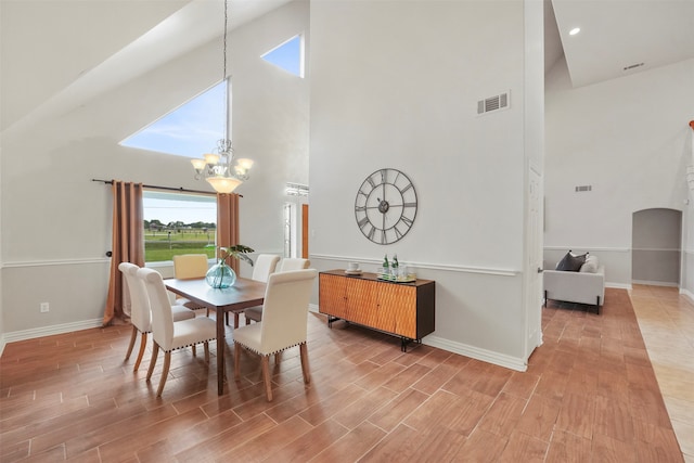 dining room featuring hardwood / wood-style flooring, a chandelier, and a high ceiling