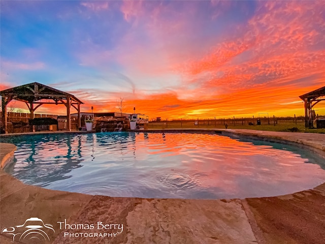 pool at dusk featuring a gazebo