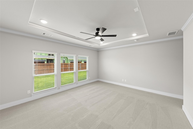 empty room featuring crown molding, ceiling fan, light carpet, and a tray ceiling