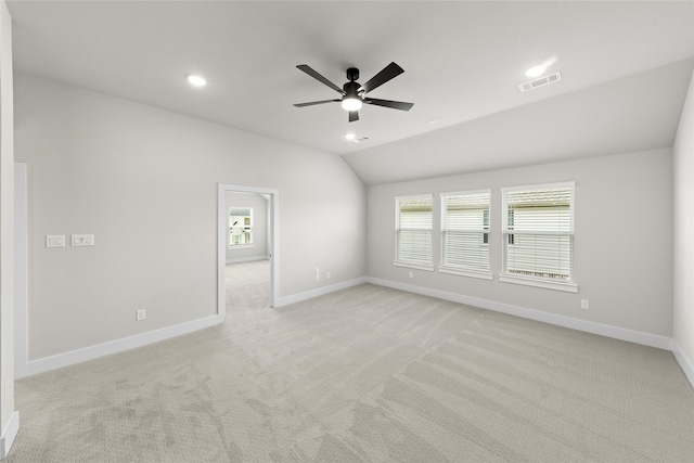 empty room with ceiling fan, light colored carpet, and vaulted ceiling