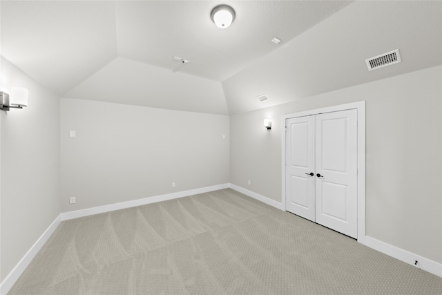 interior space featuring light colored carpet and lofted ceiling