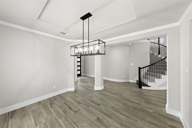 unfurnished dining area with hardwood / wood-style floors, ornamental molding, and a raised ceiling