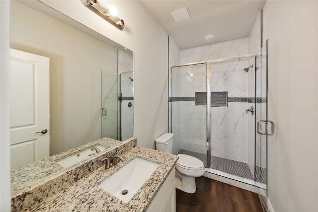 bathroom with hardwood / wood-style flooring, vanity, toilet, and a shower with shower door