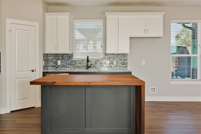 kitchen with dark wood-type flooring, backsplash, sink, and white cabinetry