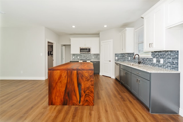 kitchen with gray cabinets, wood-type flooring, sink, white cabinets, and appliances with stainless steel finishes