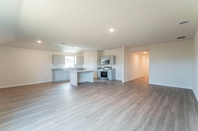 unfurnished living room with sink and light hardwood / wood-style floors