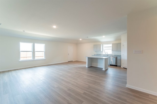 unfurnished living room featuring light hardwood / wood-style flooring, sink, and plenty of natural light