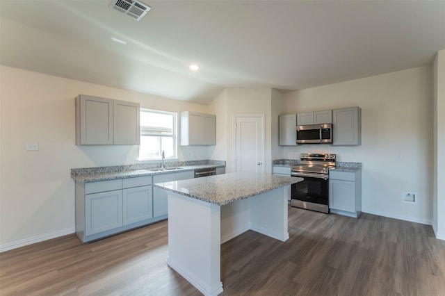 kitchen featuring gray cabinets, wood-type flooring, sink, stove, and a kitchen island