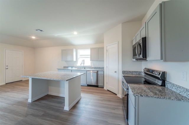 kitchen with light hardwood / wood-style flooring, stainless steel appliances, gray cabinetry, sink, and a kitchen island