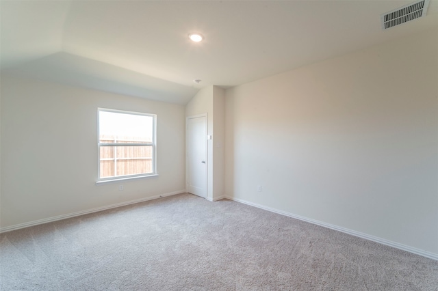 empty room with vaulted ceiling and light colored carpet