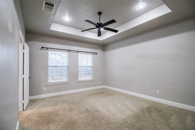 carpeted empty room featuring ceiling fan and a raised ceiling