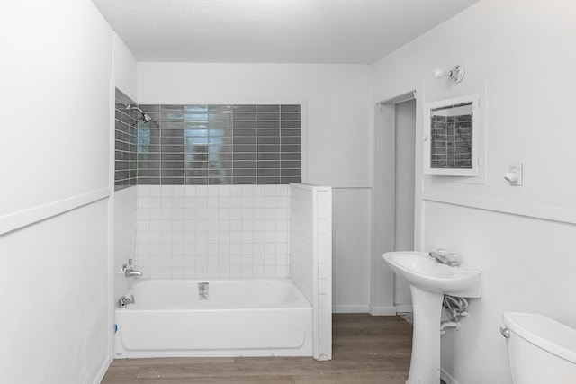 full bathroom featuring tiled shower / bath combo, wood-type flooring, sink, a textured ceiling, and toilet