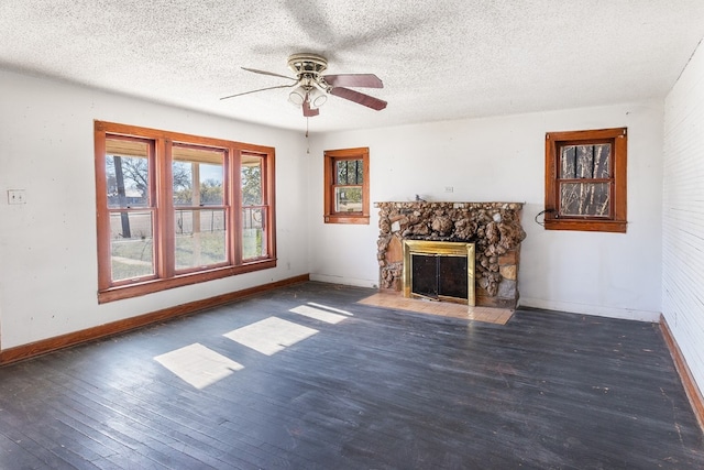 unfurnished living room with a textured ceiling, a stone fireplace, ceiling fan, and dark hardwood / wood-style floors