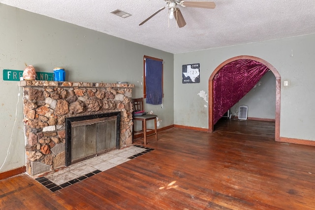 living room featuring a textured ceiling, a fireplace, ceiling fan, and hardwood / wood-style flooring