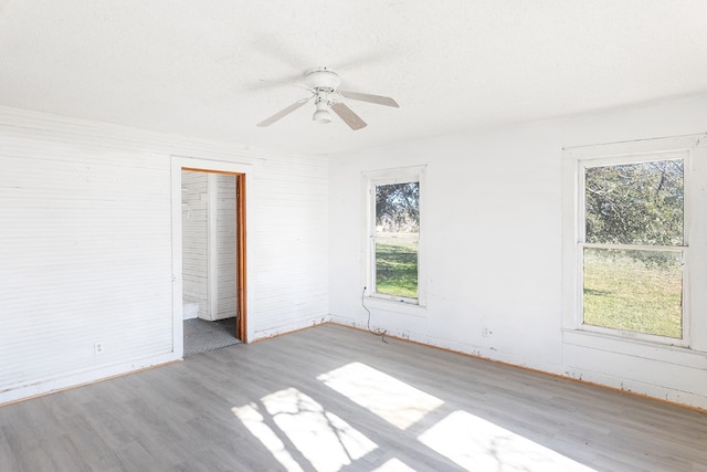 unfurnished bedroom with a closet, multiple windows, ceiling fan, and light wood-type flooring