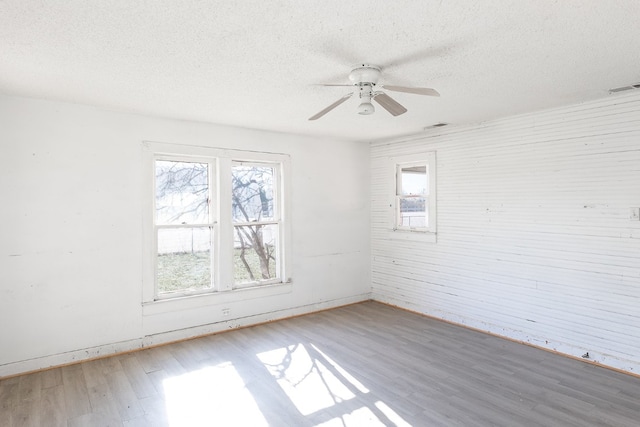 empty room featuring ceiling fan, a textured ceiling, and hardwood / wood-style flooring