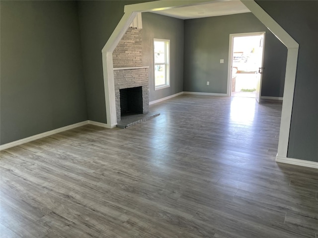 unfurnished living room with brick wall, dark wood-type flooring, and a fireplace