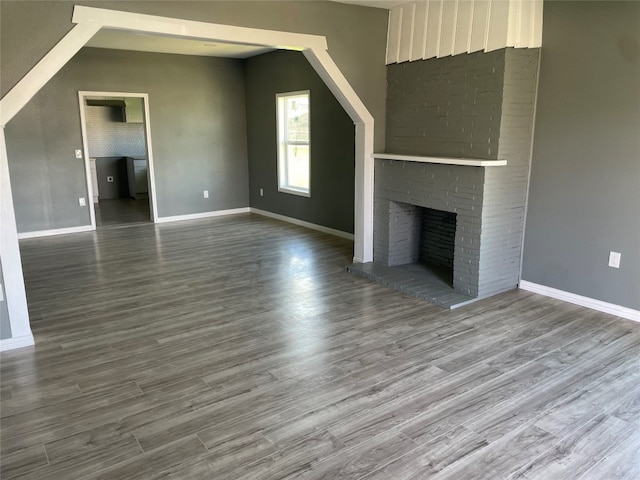 unfurnished living room featuring brick wall, dark wood-type flooring, and a fireplace