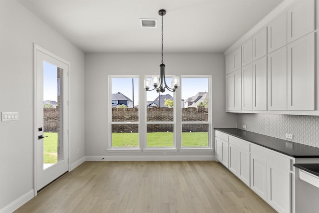 unfurnished dining area with a chandelier and light wood-type flooring