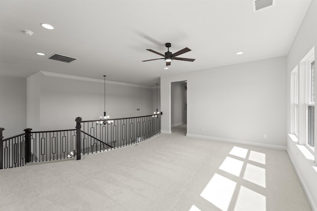 unfurnished room with ceiling fan with notable chandelier and light colored carpet