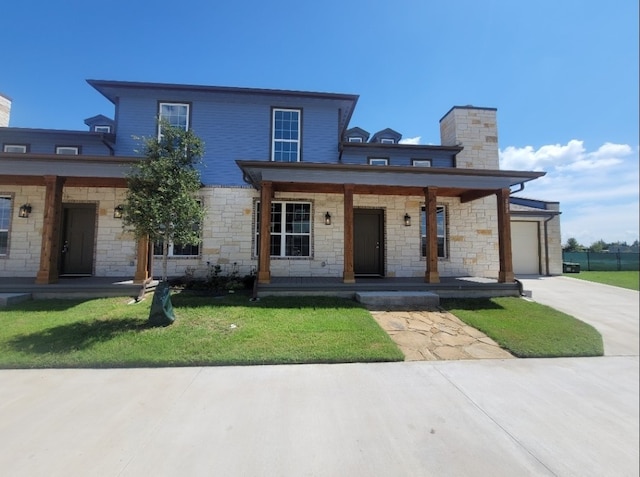 view of front of home featuring a front yard, covered porch, and a garage