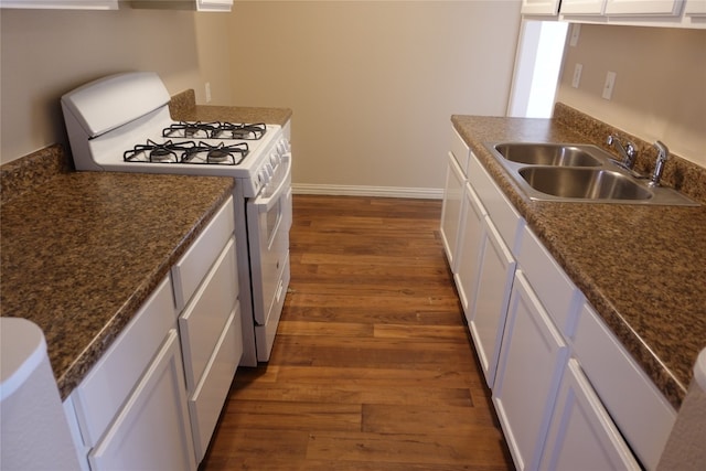 kitchen featuring dark stone counters, dark wood-type flooring, white gas range oven, white cabinets, and sink