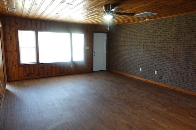 unfurnished room with wooden ceiling, ceiling fan, dark wood-type flooring, and brick wall