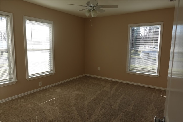 empty room with ceiling fan, a wealth of natural light, and dark colored carpet