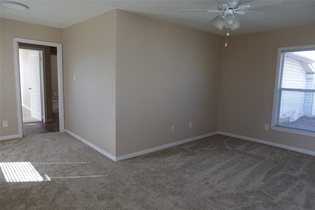 spare room featuring ceiling fan and dark colored carpet